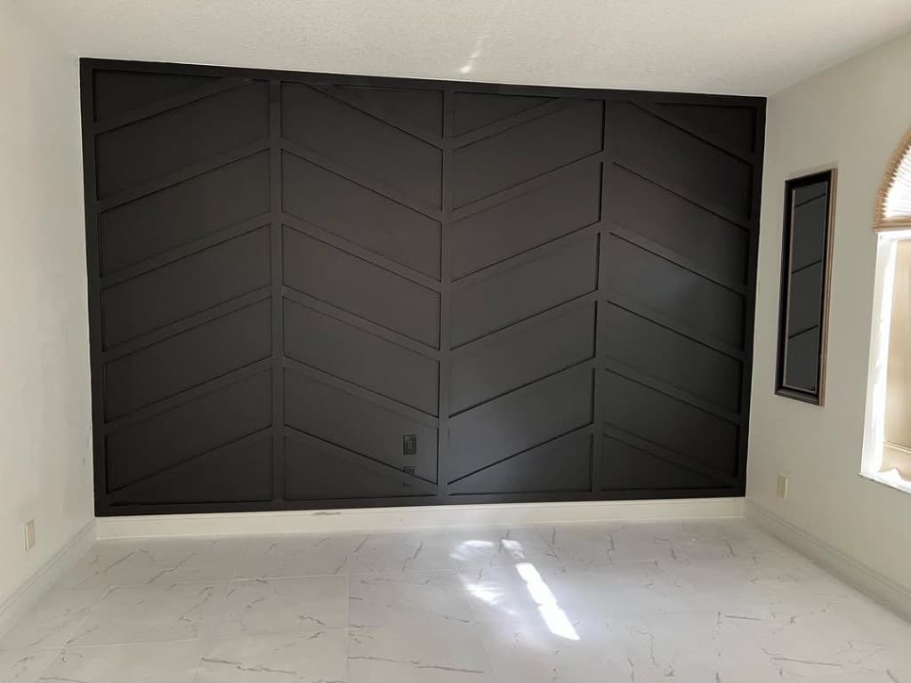 Interior dramatic black geometric panel wall symmetrical angles white walls marble plank flooring outlet flush black fascia.