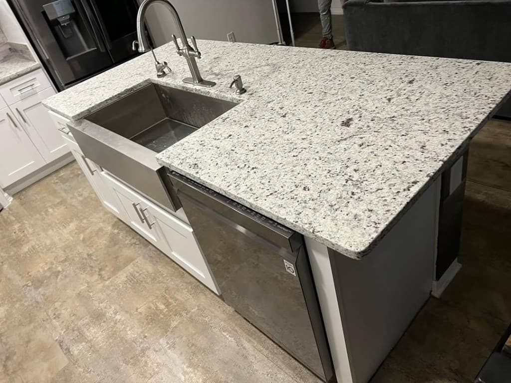 Kitchen island apron front stainless sink brushed faucet dishwasher door white shaker lowers speckled granite wide.