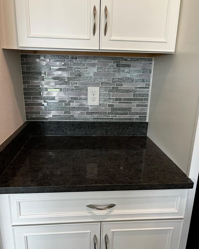 Kitchen backsplash corner metallic mosaic mixed glass stone black granite lip white shaker lowers outlets centered symmetry.